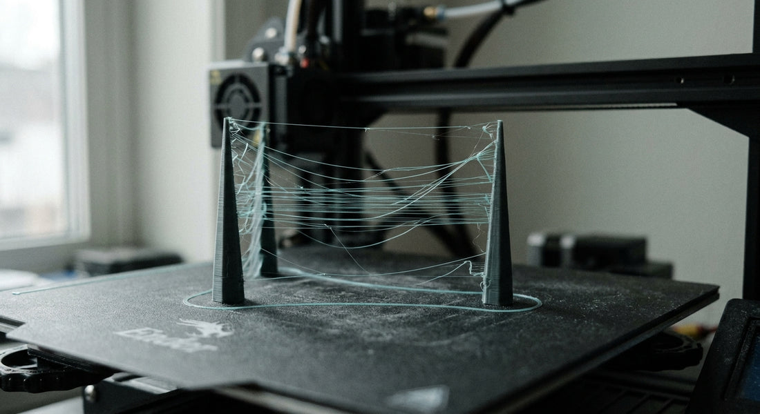 Stringing w druku 3D — cienkie nitki filamentu rozpięte między dwiema wieżami testowymi
